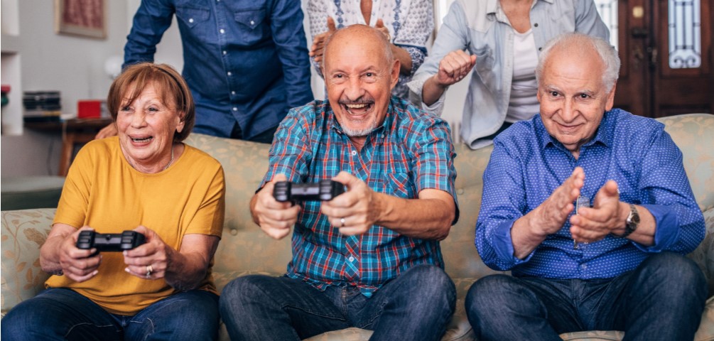 three older adults are on a couch playing video game