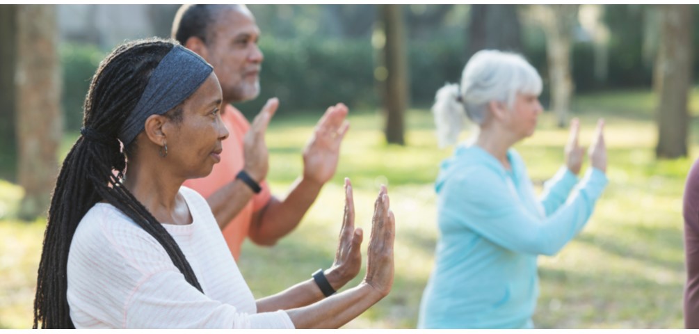 A group of older adults participate in tai chi outdoors