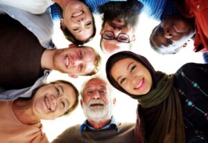 a group of people from all races and ages are in a circle smiling and looking at the camera