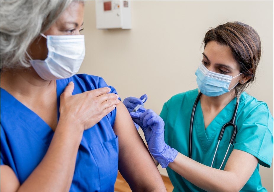 older adult woman receives a vaccine shot from a nurse