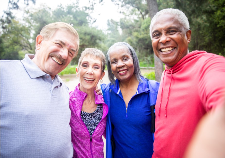 two older adult couples pose together outside