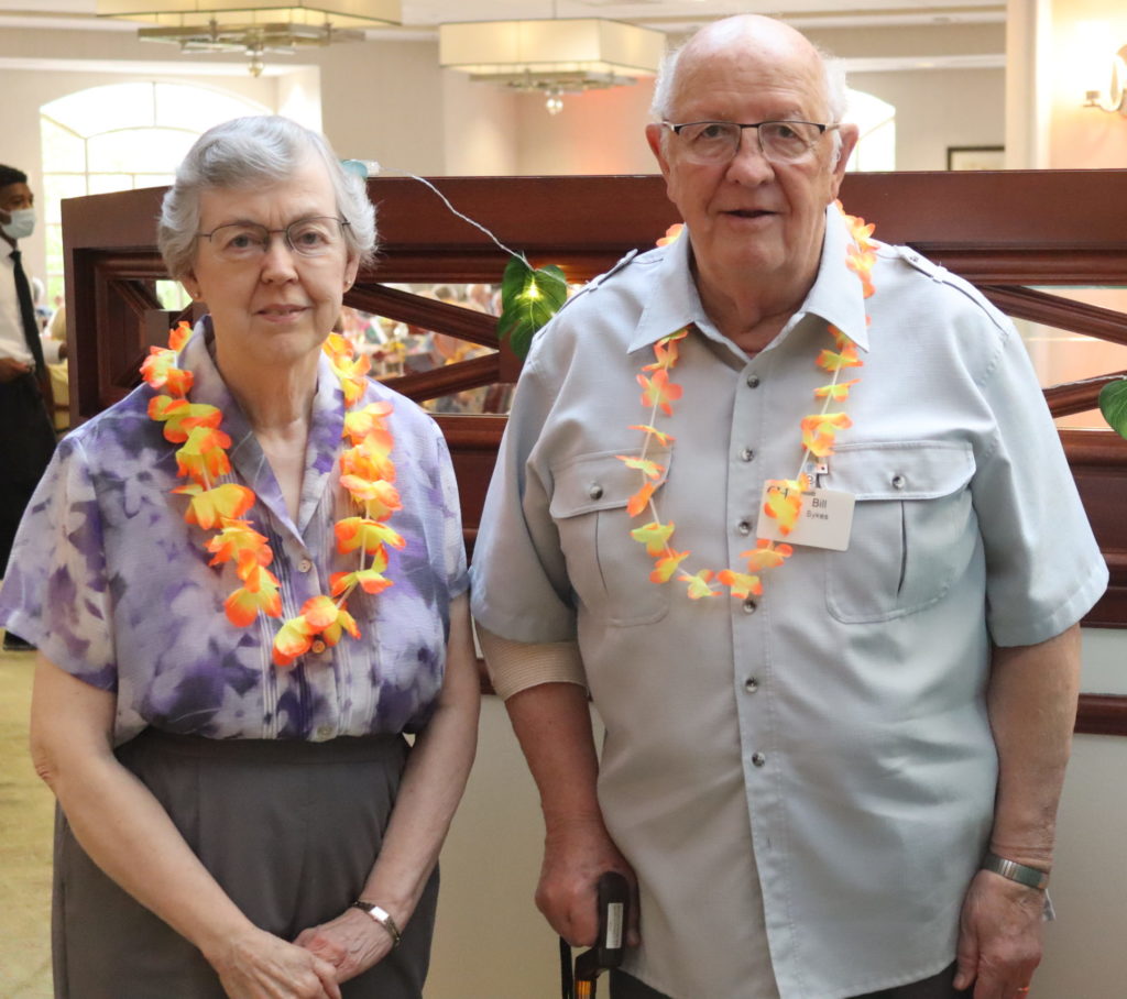 a wife and husband pose for a photo at a Hawaiian event