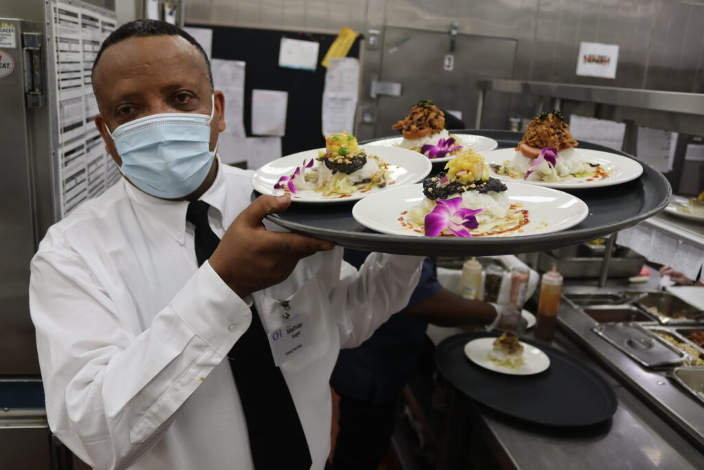 dining services team member carries a large tray of food