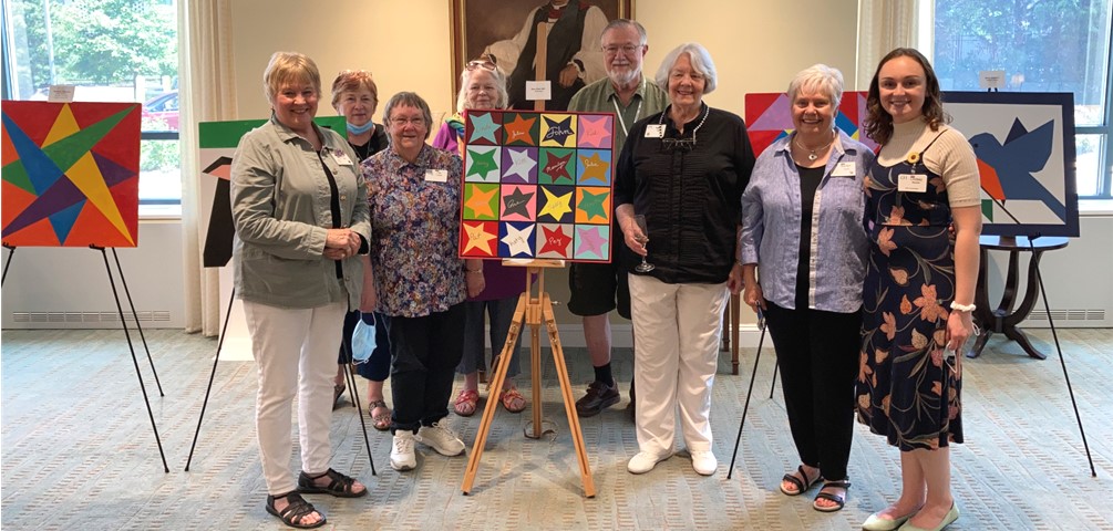 GHA residents stand next to the barn quilts they created for the Stonebrook patio