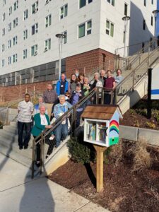 residents, staff and church members pose on a stairwell next to the Little Free Library