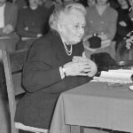 Maria Montessori sits at desk
