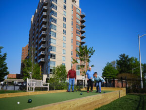 three older adults play bocce ball outside
