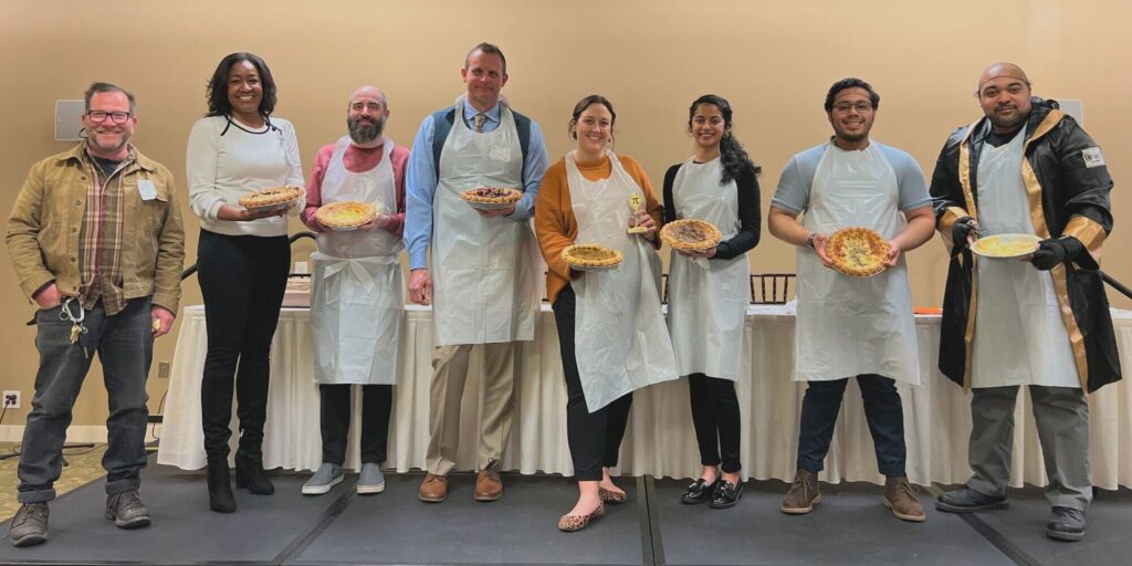 Goodwin Living team members hold their pies ahead of the pie eating competition on pi day