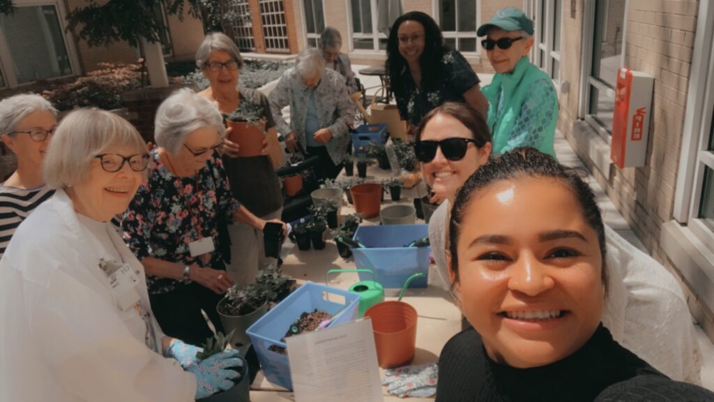 a group of people ranging in different ages gather around a table to plant herb gardens