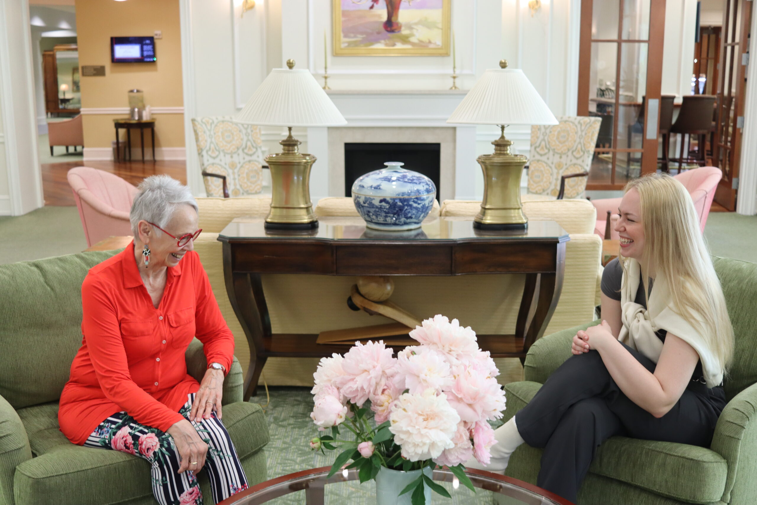 GHBC resident sits in a lobby with an intern as they chat.