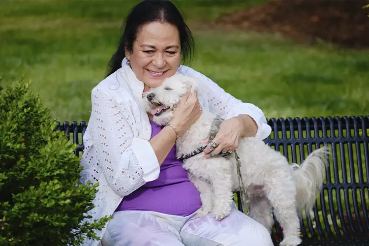 Older adult enjoying outside with her dog.