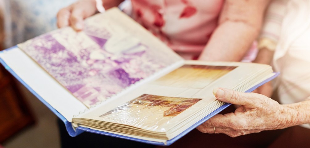 a century of stories. two older women hold an open photo album on their laps