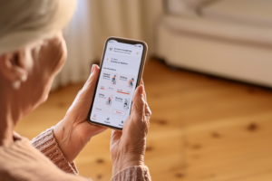 an older woman holds up a phone with the screen showing the Vitala app homepage