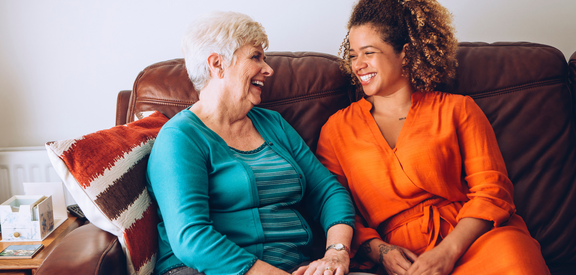 Parkinson's Awareness. older woman in blue talks to younger woman in orange while they sit on a couch