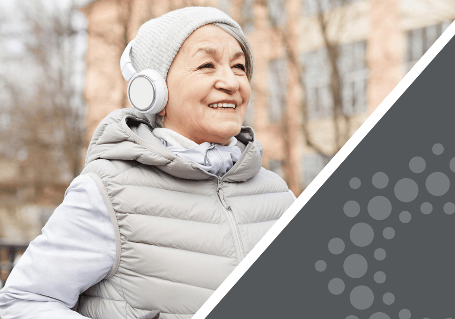 senior woman wearing headphones jogging outside in winter