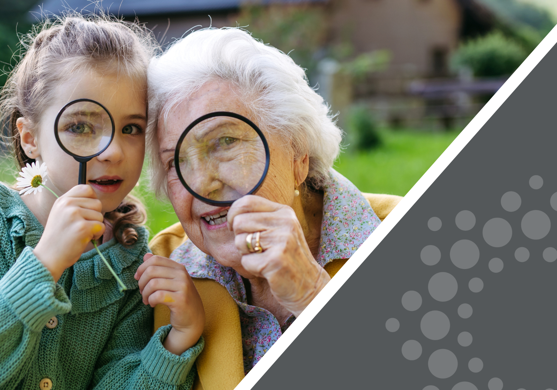 grandmother and granddaughter hold up magnifying glasses to their eyes as they smile at the camera