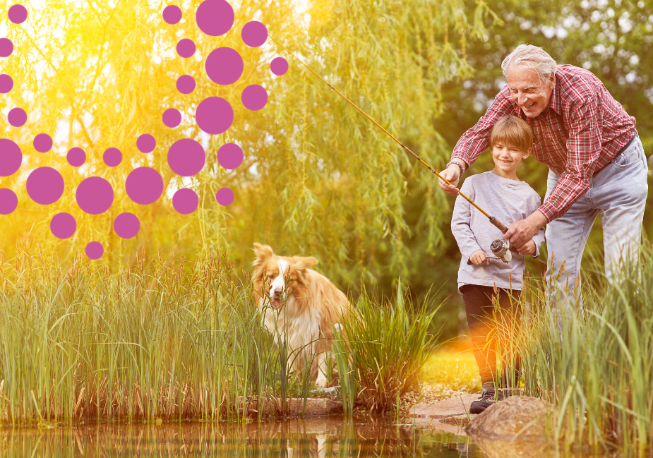 grandfather fishing with young grandson as their dog looks on