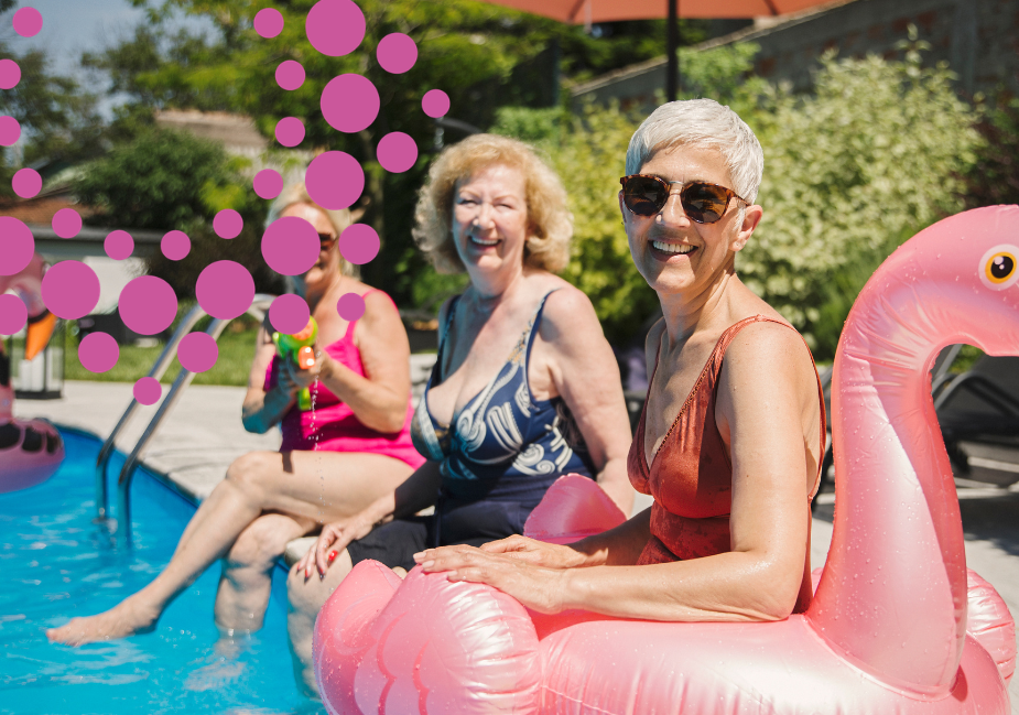 older women sit by the pool in their swimsuits with a pink inflatable